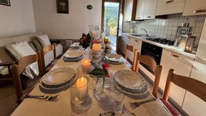 Una mesa de comedor servida con platos, velas y cubiertos en una habitación con vigas de madera y vistas al exterior.