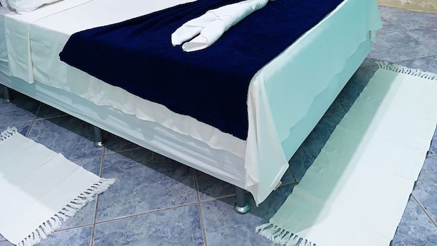 A hotel room with a bed, a nightstand, an air conditioning unit, a painting, and a blue curtain. - Casa Porto Hospedaria (Ipojuca)