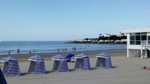 Uma praia com guarda-sóis listrados e uma torre de salva-vidas.
