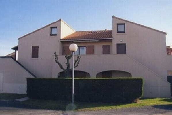 Un immeuble de deux étages, doté d’un toit plat et d’un petit balcon au deuxième étage.