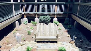 A wooden bench in a garden area with a stone pathway leading up to it.