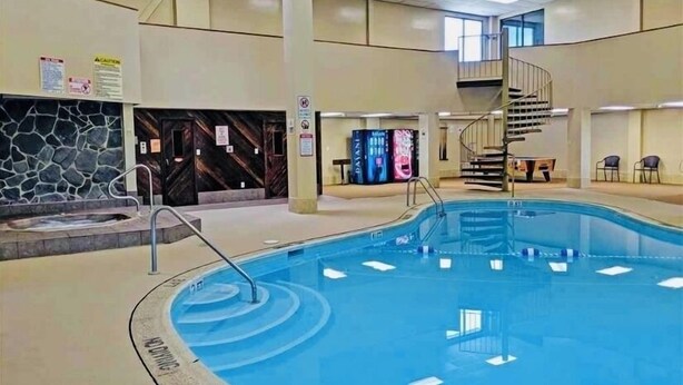 An indoor swimming pool with a stone wall, a staircase, and a digital display.