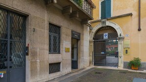 A building with a stone facade, a metal gate, and a small balcony with plants.