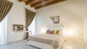 A bedroom with a bed, a bedside table, a picture frame, and a window with curtains.