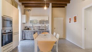 A modern kitchen with a built-in oven, a dining table with chairs, and a pendant light.
