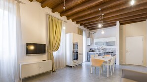 A modern kitchen with white cabinets, a built-in oven, and a dining area with a table and chairs.