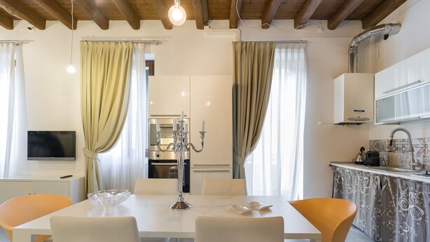 A modern kitchen with white cabinets, a built-in oven, and a stainless steel sink.
