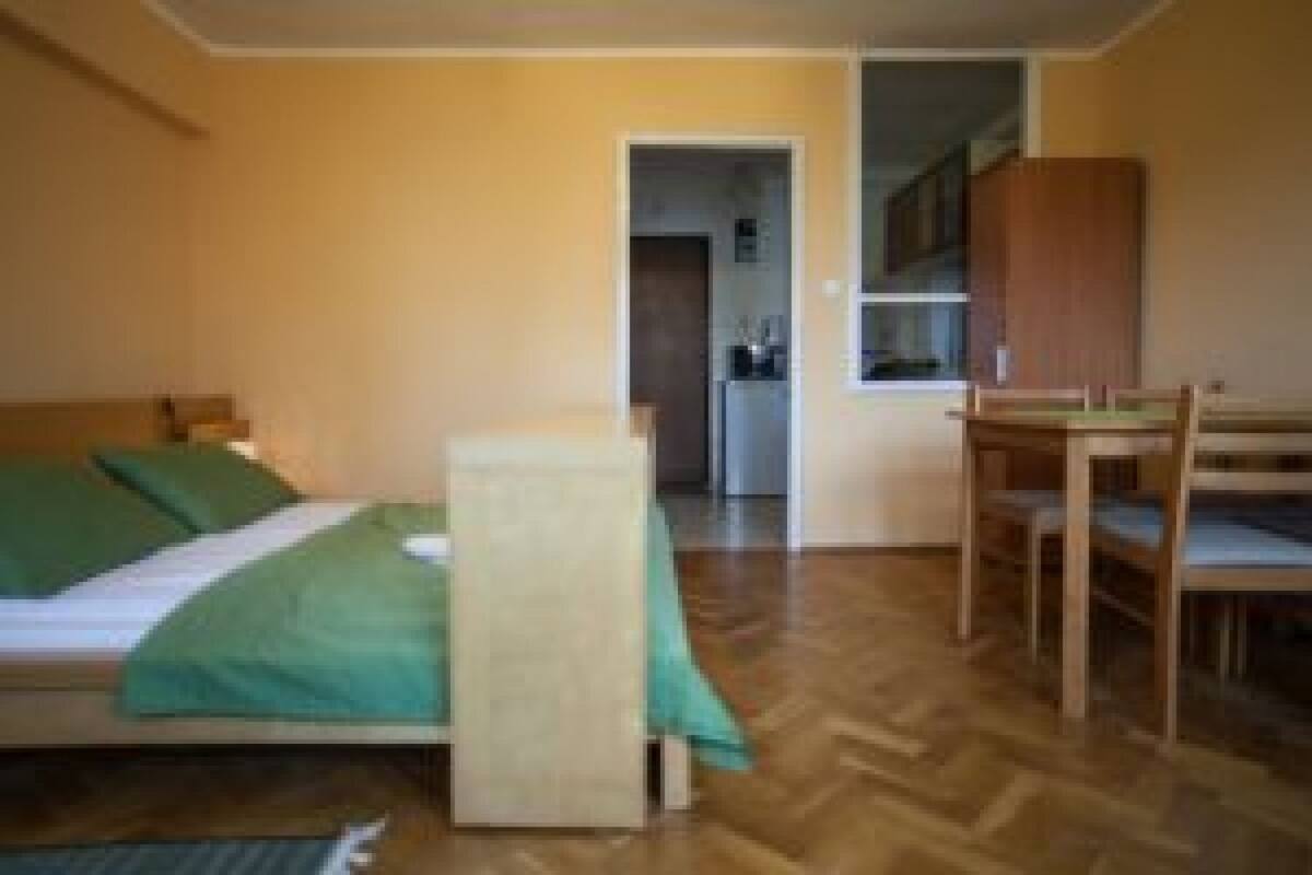 A small, compact room with a bed, a desk, and a kitchenette area.