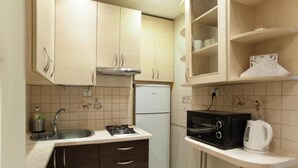A compact kitchen with a sink, stove, microwave, and a refrigerator. - Apartamenty Varsovie Chmielna (Warsaw)