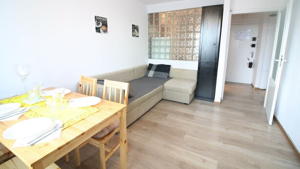 A modern living room with a dining area, a sofa bed, and a glass partition wall. - Apartamenty Varsovie Chmielna (Warsaw)