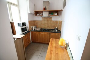 Una cocina compacta con armarios de madera, microondas, estufa y una pequeña encimera.