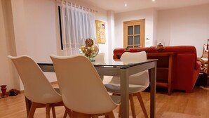 A dining area with a glass table and white chairs, a red sofa, and a wooden floor. - Casa Galipendre, in the heart of Galicia (A Estrada)