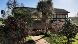 A house with a tiled roof, surrounded by a garden with red flowers and a wooden fence. - Casa Galipendre, in the heart of Galicia (A Estrada)