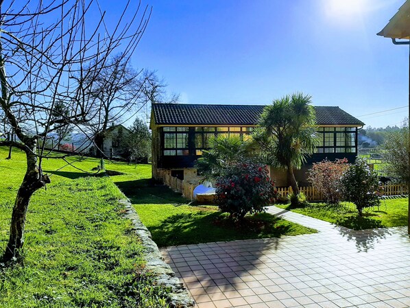 A two-story house with a tiled roof, surrounded by a well-maintained lawn and a stone pathway leading to the entrance. - Casa Galipendre, in the heart of Galicia (A Estrada)