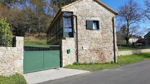 A stone building with a green gate, a small window, and a number '24' on a stone wall. - Casa Galipendre, in the heart of Galicia (A Estrada)