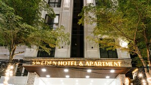 A hotel with a prominent sign, a staircase leading to the entrance, and outdoor seating. - SWEDEN Hotel and Apartment (Da Nang)