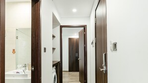 A hallway with a washing machine, a sink, and a door leading to a room. - SWEDEN Hotel and Apartment (Da Nang)