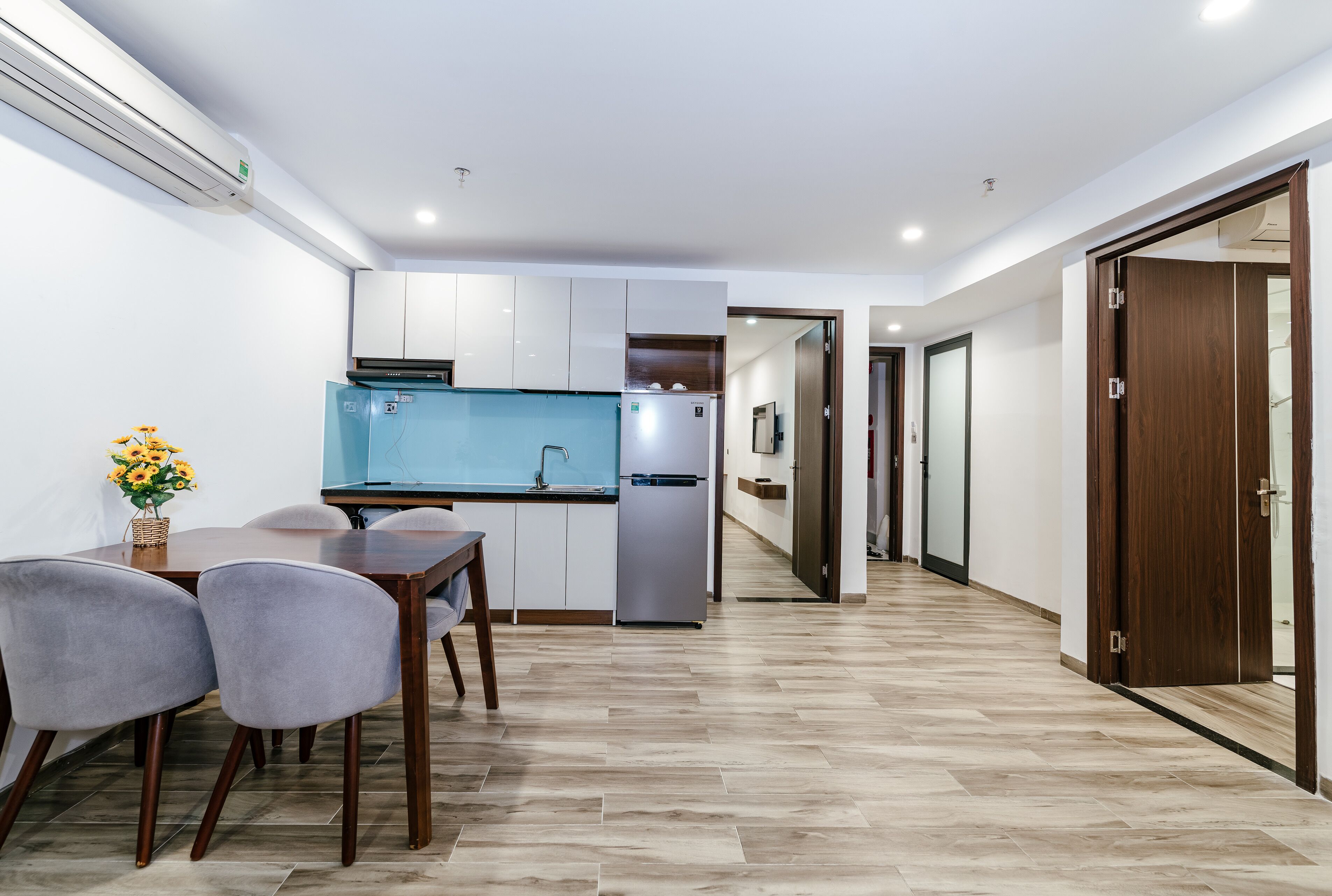 A modern kitchen with white cabinets, a blue countertop, and a stainless steel refrigerator.