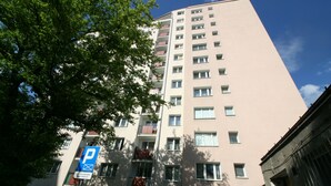 En byggnad med flera våningar, en parkeringsskylt, balkonger och en klar himmel.