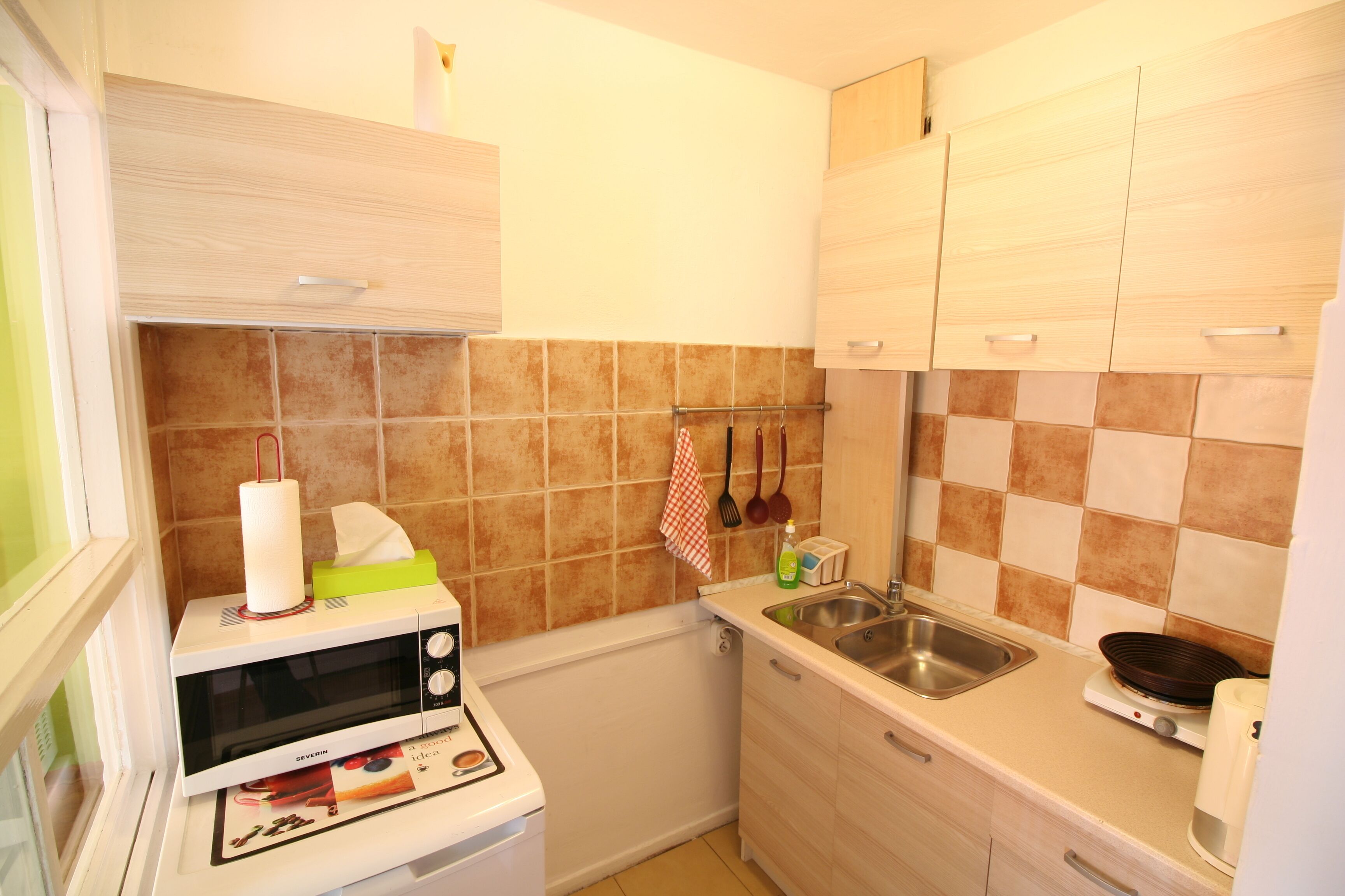 Cocina compacta con microondas, pileta y alacenas.