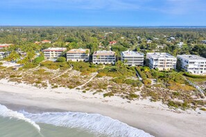 A beachfront hotel with multiple buildings, sandy beach, and ocean waves.