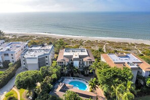 Un hôtel situé sur la côte, composé de plusieurs bâtiments, doté d’une piscine et offrant une vue sur la plage.