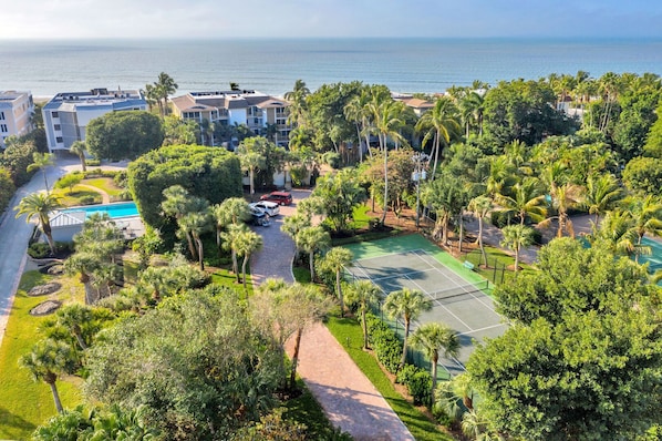 A residential area with a tennis court, swimming pool, and a view of the ocean.