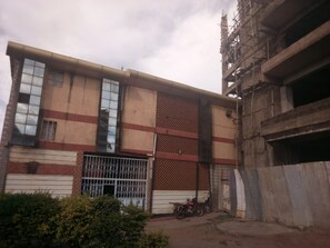 Un bâtiment doté d’un grand portail de garage, d’une clôture en métal et d’une moto garée devant.
