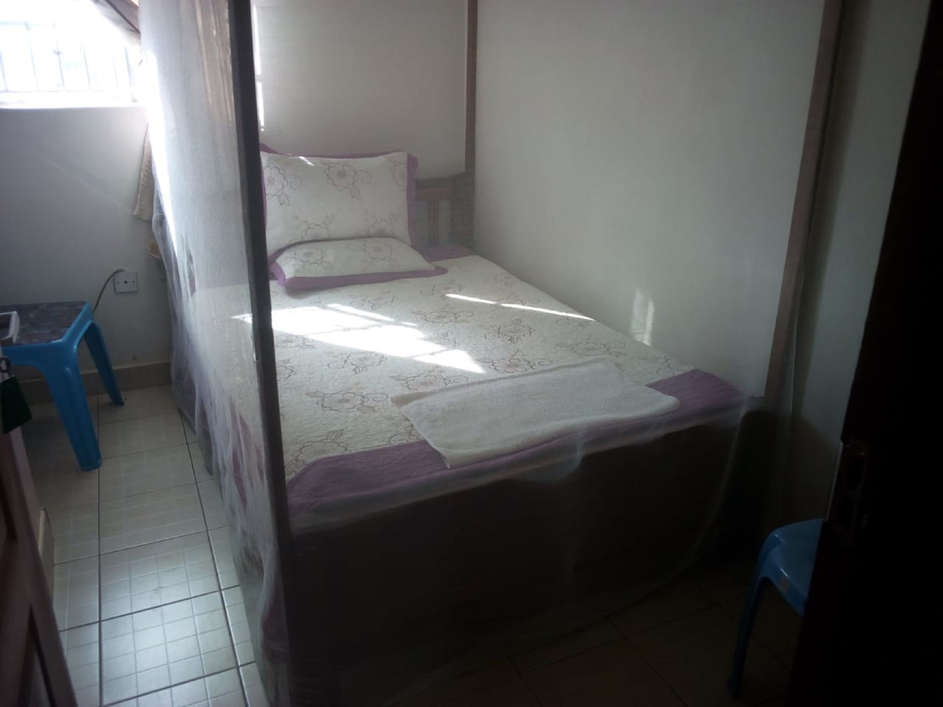 A small, single-bed room with a simple bed, a small table, and a chair.