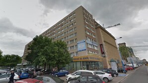 A multi-story building with a commercial ground floor, featuring a sign for a business named "ODZIEZ NA WAGE." - Apartamenty Varsovie Jerozolimskie City (Warsaw)