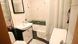 A bathroom with a white sink, a toilet, a bathtub, and a shower curtain. - Apartamenty Varsovie Jerozolimskie City (Warsaw)