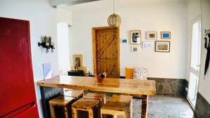 Une cuisine avec un îlot central en bois, des tabourets, un réfrigérateur rouge et une porte en bois.