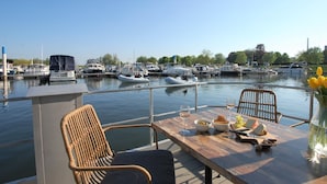 A dining table with a view of a marina filled with boats. - Cozy floating Boatlodge "Mallorca", Max. 4 pers, 2 bedrooms. (Maastricht)