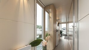 A modern kitchen with a view of the water, a dining area, and a hallway leading to a bedroom. - Cozy floating Boatlodge "Mallorca", Max. 4 pers, 2 bedrooms. (Maastricht)
