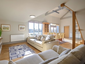 A spacious living room with a sofa, a dining table, and a staircase.