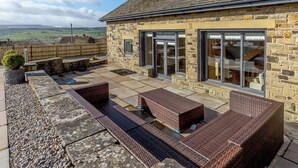 A stone house with a patio, outdoor furniture, and a view of the countryside.