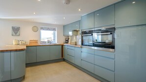 A modern kitchen with built-in appliances, a window with a view, and a clock on the wall.