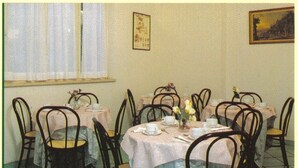 A dining room with round tables, chairs, and a window with blinds. - Hotel San Francesco Inn (Stroncone)