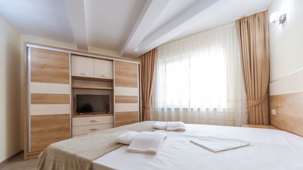 Una habitación de hotel moderna con una cama grande, televisión y armario.