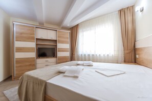 A modern hotel room with a large bed, a TV, and a wardrobe. - Dany Luxury Apartment (Pitesti)