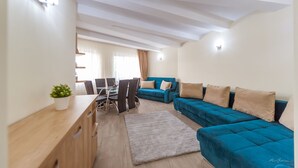Una sala de estar moderna con un sofá azul, una mesa de centro de madera y una zona de comedor con una mesa y sillas.
