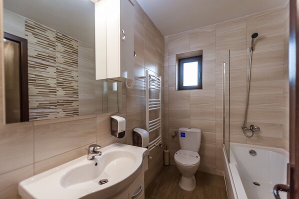 A modern bathroom with a sink, toilet, and bathtub. - Dany Luxury Apartment (Pitesti)