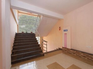 Una escalera que conduce al primer piso, con un extintor en la pared y una puerta con una franja rosa.