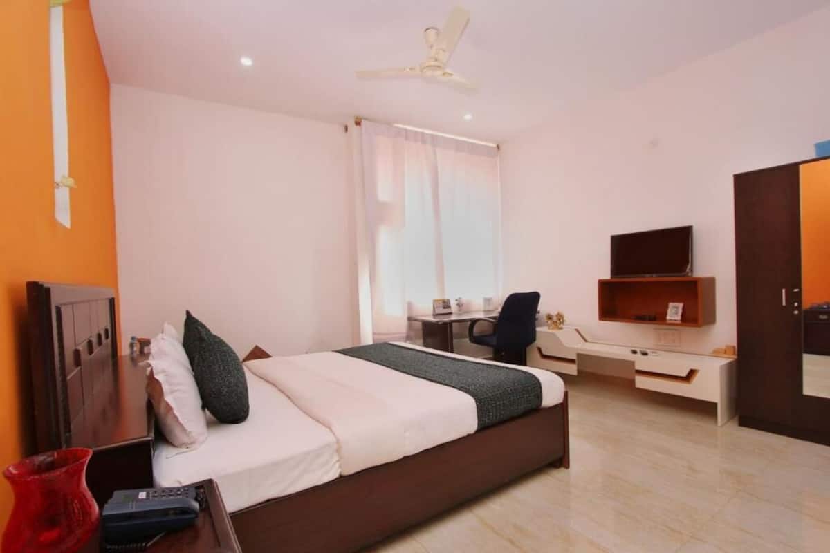 Een hotelkamer met een bed, bureau, stoel, televisie en kledingkast.