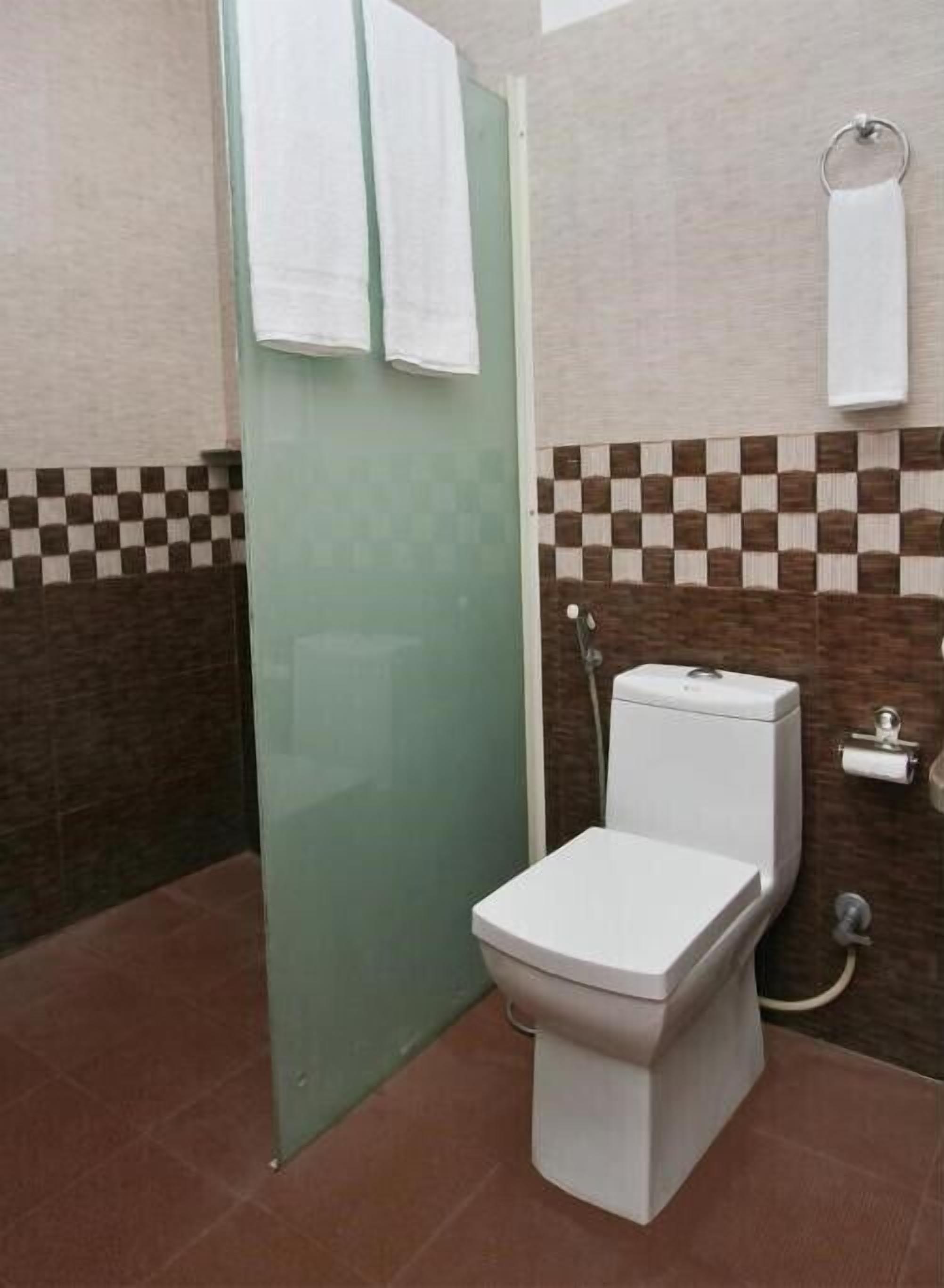 A bathroom with a toilet, a glass shower door, and a towel rack.