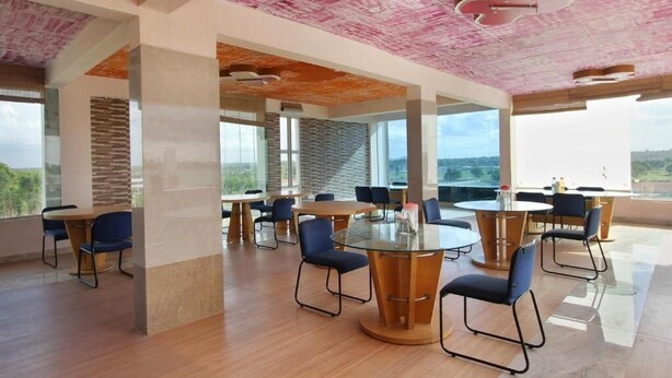 A modern conference room with glass tables and chairs, large windows, and a unique ceiling design.