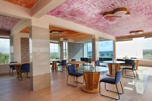 A modern conference room with glass tables and chairs, large windows, and a unique ceiling design.
