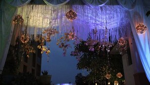 A decorated outdoor area with draped fabric and hanging floral arrangements.