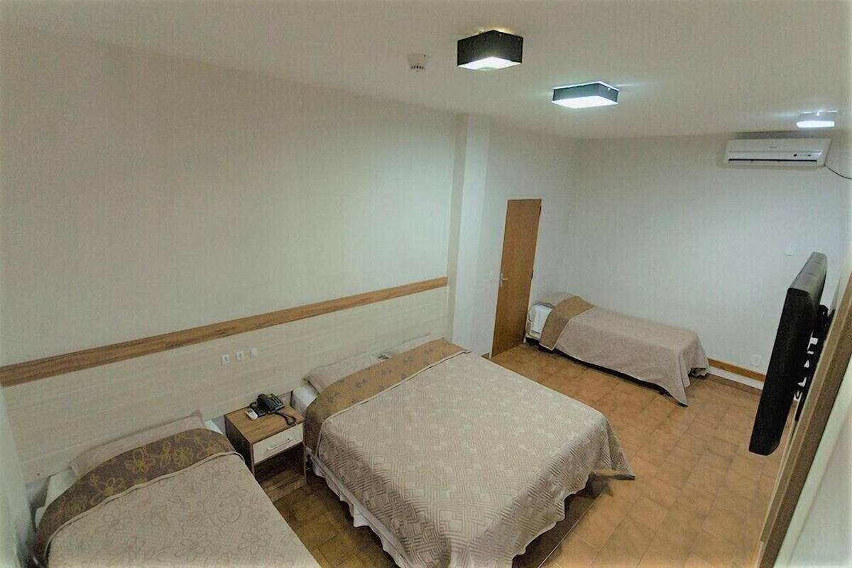 Habitación de hotel con dos camas, una mesita de noche, un televisor y un equipo de aire acondicionado.