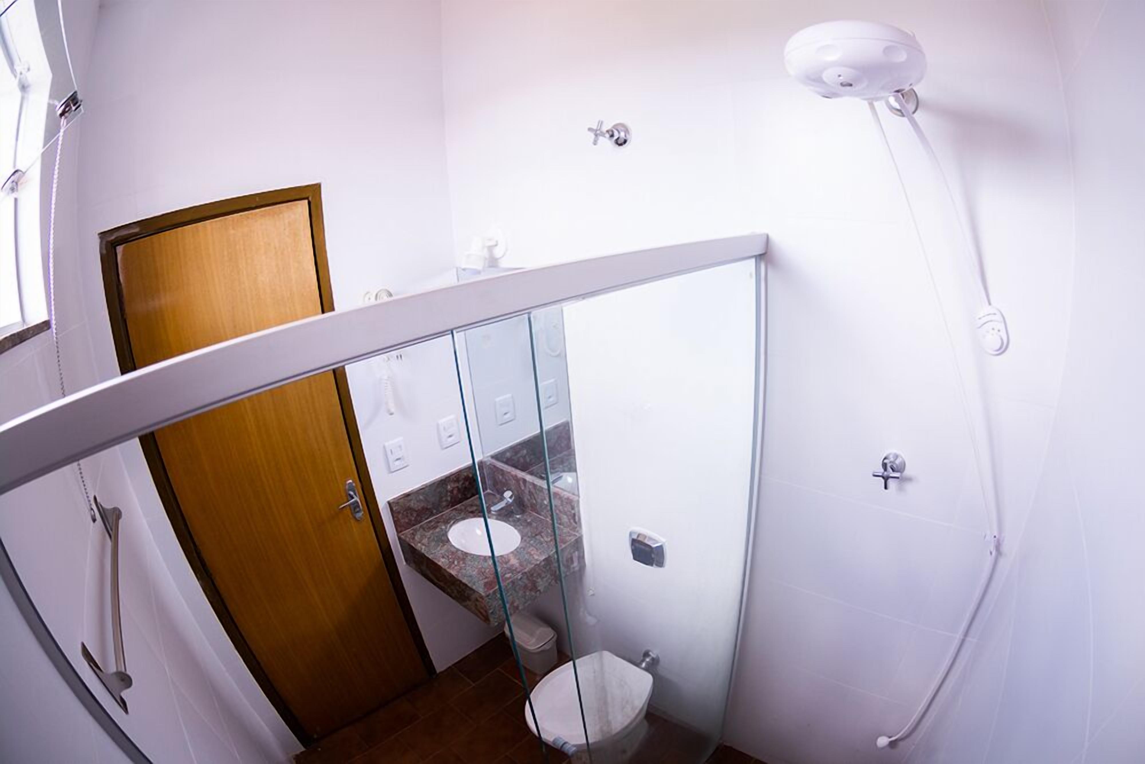 A bathroom with a glass partition, a wooden door, a marble sink, and a white toilet.